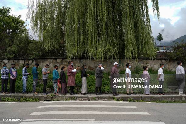 People queue up to register themselves and get inoculated with the Covid-19 coronavirus vaccine at a temporary vaccination centre in Thimpu on July...