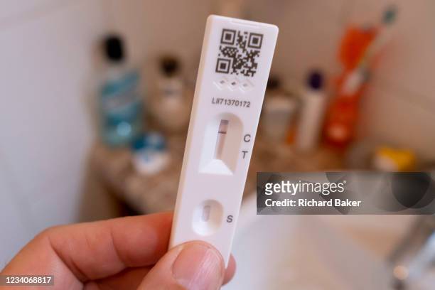 Detail of a hand holding a lateral flow test that shows a negative result in a domestic bathroom on 'Freedom Day', 19th July 2021, in London,...