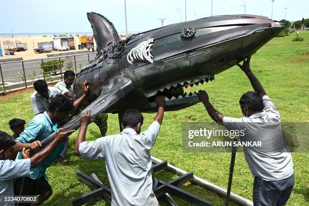 Workers install a sculpture made of scrap iron at Marina beach in Chennai on July 20, 2021.