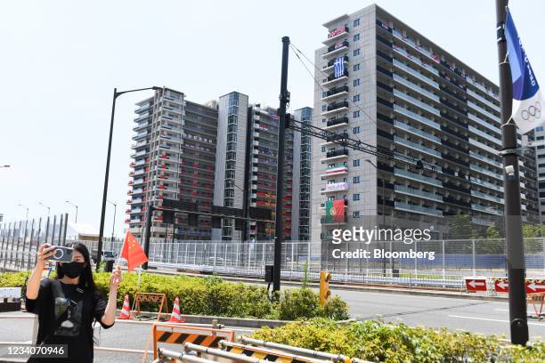 Visitor takes a selfie photograph in front of residential buildings in the Olympic and Paralympic Village for the Tokyo 2020 Games in Tokyo, Japan,...