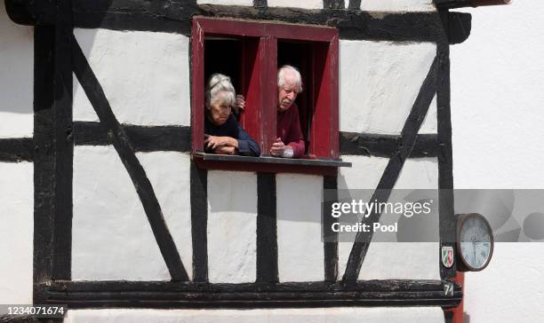 Couple look out from a window as German Chancellor Angela Merkel and Prime Minister of North Rhine-Westphalia Armin Laschet inspect the damage after...