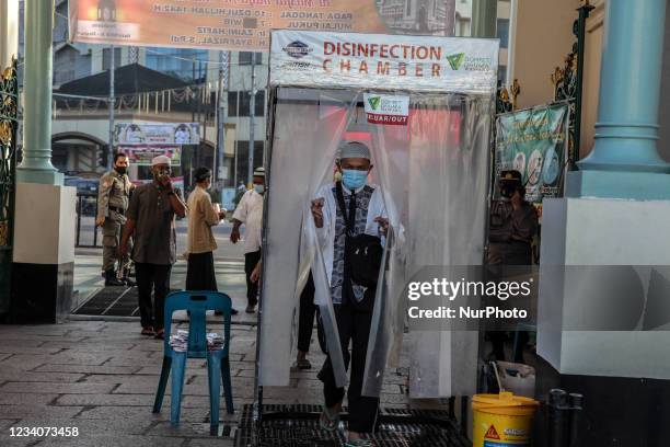 Indonesian muslims walk through a disinfection chamber installed to curb the spread of coronavirus outbreak as they enter Al Mashun Great Mosque to...