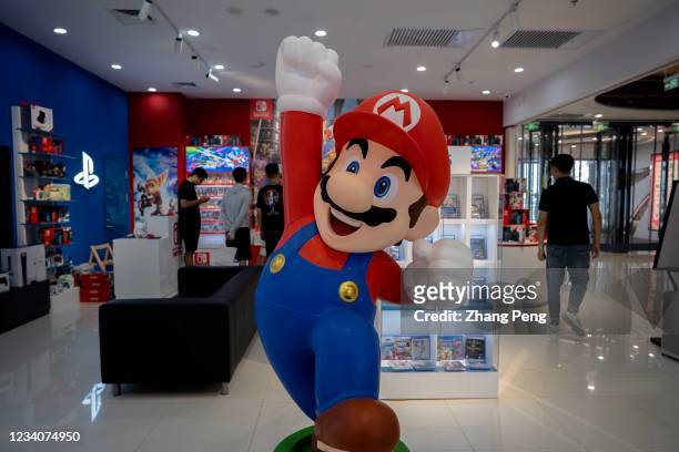 Cartoon figurine of Super Mario Bros. Stands in front of a Nintendo Switch store in a shopping market. By the end of June 2021, Nintendo's total...