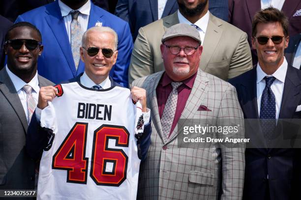 President Joe Biden holds up a Buccaneers jersey while standing next to linebacker Devin White, head coach Bruce Arians, and quarterback Tom Brady as...