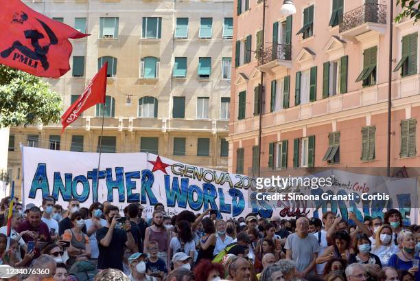 People stand in front of a banner saying: another world is still possible, as they participate at the demonstration in Piazza Alimonda where Carlo...