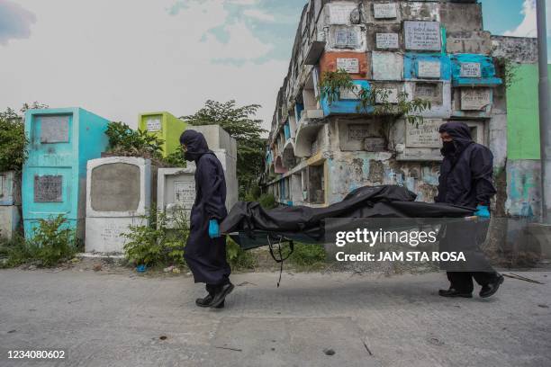 This photo taken July 8, 2021 shows workers wearing masks, gloves and protective coats as they carry a body bag containing the skeletal remains of...