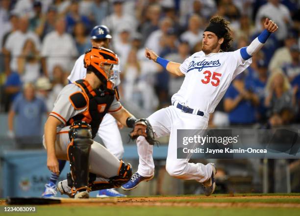 Cody Bellinger of the Los Angeles Dodgers scores ahead of the throw to catcher Buster Posey of the San Francisco Giants on a double off the bat of...