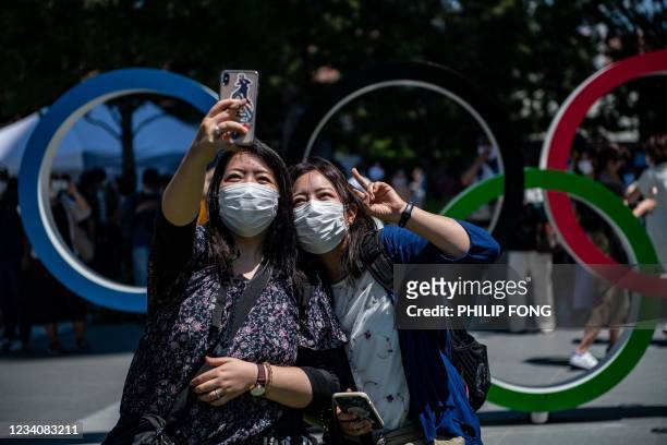 Women take a selfie picture in front of the Olympic Rings near the Olympic Stadium in Tokyo, on July 21, 2021 ahead of the Tokyo 2020 Olympic Games.