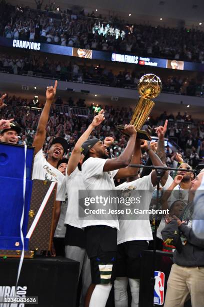 Khris Middleton of the Milwaukee Bucks celebrates with the Larry O'Brien Trophy after winning Game Six of the 2021 NBA Finals against the Phoenix...