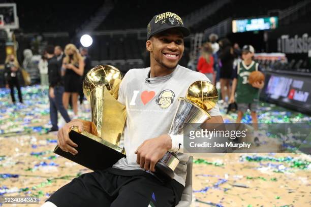 Giannis Antetokounmpo of the Milwaukee Bucks smiles with the Larry O'Brien Trophy and the Bill Russell Finals MVP Award after winning the 2021 NBA...