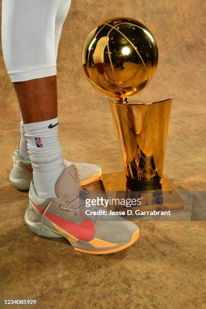 The sneakers of Giannis Antetokounmpo of the Milwaukee Bucks are seen with the Larry O'Brien Trophy after winning Game Six of the 2021 NBA Finals...