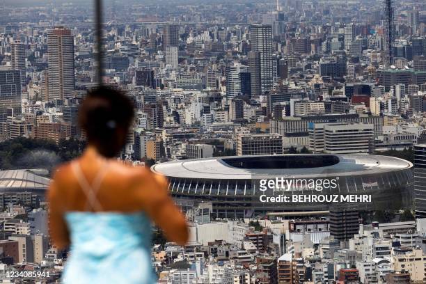 Woman looks at the Olympic Stadium from the Shibuya Sky observation deck in Tokyo on July 21, 2021 ahead of Tokyo 2020 Olympic Games.