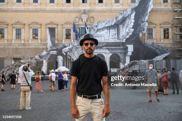 French contemporary artist JR poses in front of his art installation "Punto di Fuga" on the facade of Palazzo Farnese, on July 21, 2021 in Rome,...