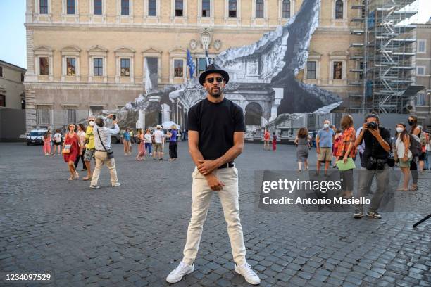 French contemporary artist JR poses in front of his art installation "Punto di Fuga" on the facade of Palazzo Farnese, on July 21, 2021 in Rome,...