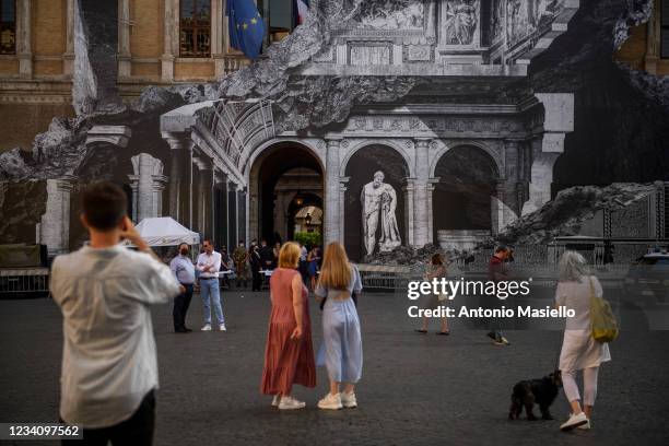 People look at the art installation "Punto di Fuga" by the French contemporary artist JR, on the facade of Palazzo Farnese, on July 21, 2021 in Rome,...