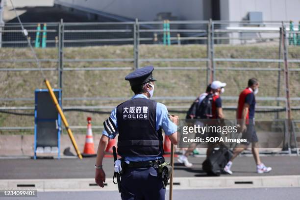 Police officer watches over French Olympic Team members as they enter the security checkpoint right outside of the Tokyo 2020 Olympic Village in...
