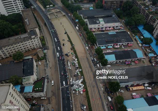 An aerial view shows cars sitting in floodwaters at the entrance of a tunnel after heavy rains hit the city of Zhengzhou in China's central Henan...