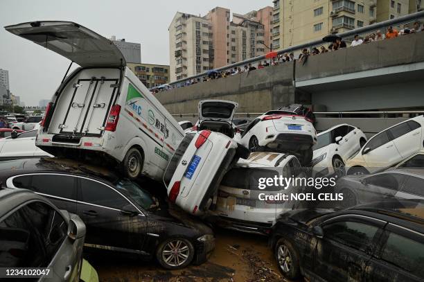 People look at cars sitting in floodwaters following heavy rains, in Zhengzhou in China's central Henan province on July 22, 2021.