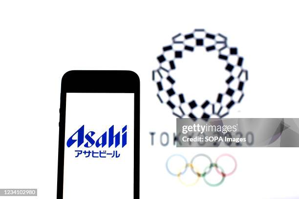 In this photo illustration an Asahi Breweries, Ltd logo seen displayed on a smartphone with a Tokyo 2020 Olympic Games logo in the background.