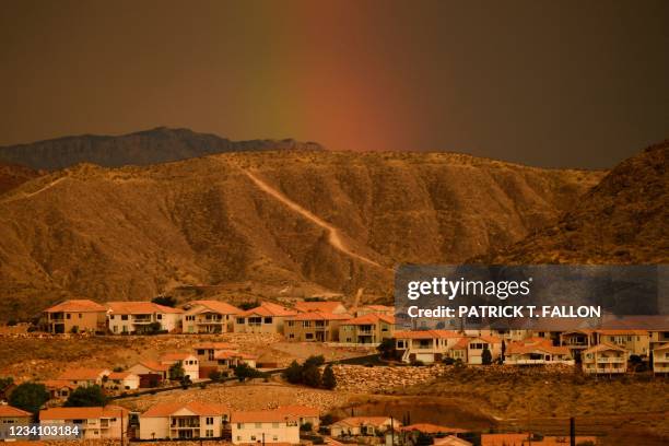 Rainbow shines behind homes on a hillside during the western drought on July 20, 2021 in St. George, Utah. - An approximately 140-mile water pipeline...