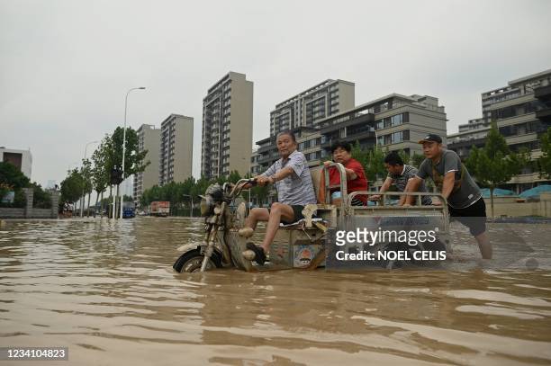 People wade through a flooded street following a heavy rain in Zhengzhou, in China's Henan province on July 22, 2021.