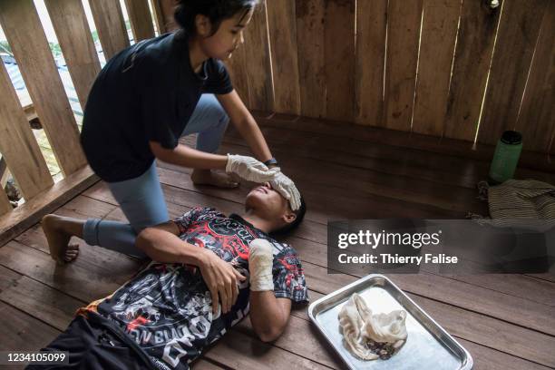 Female medic from the Free Burma Rangers helps Kalay, a young man victim of a anti-personnel mine, to lay down for a dressing change. The FBR is a...