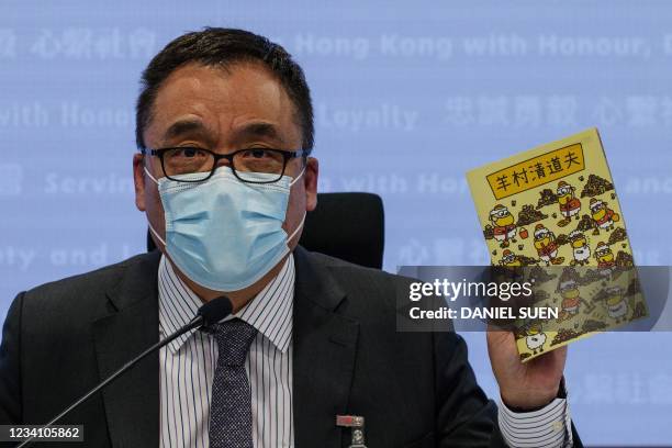 Hong Kong's senior superintendent Steve Li, from the city's new national security police unit, holds up a children's book which allegedly tries to...