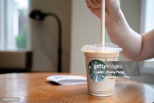 Customer is using a paper straw to drink a cold Starbucks latte. To fulfill the social responsibility of environmental protection, Starbucks has...