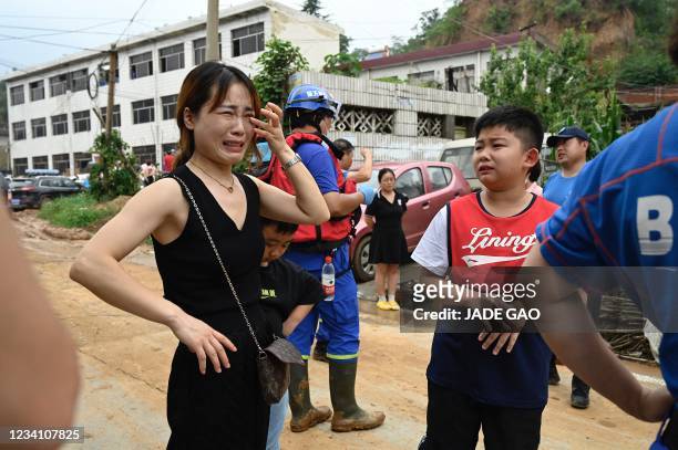 Woman and a boy cry to rescuers for help after being separated from their family members after severe flooding and landslide in recent days have hit...
