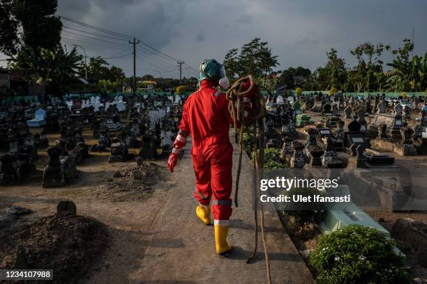 Volunteer prepares conduct a burial the body of a woman suspected to have died from COVID-19 while isolating at home on July 22, 2021 in Yogyakarta,...