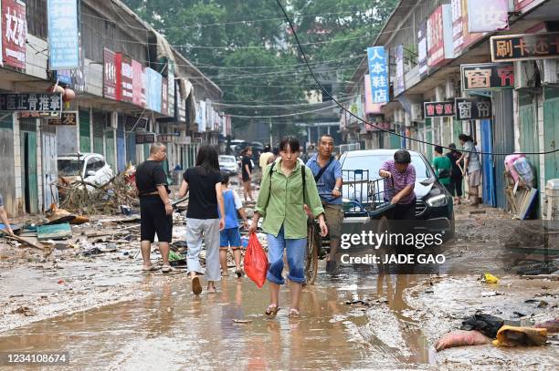 Woman carries a bag on a muddy street after severe flooding and landslide in recent days have hit the county-level Gongyi city, near Zhengzhou, in...