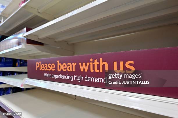 Sign requesting shoppers' patience about products temporarily out of stock is displayed on empty shelves in a supermarket at Nine Elms, south London...