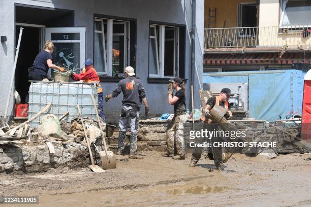 Workers form a human chain to remove buckets full of mud from a building in Dernau near Bad Neuenahr-Ahrweiler, western Germany, on July 22 days...