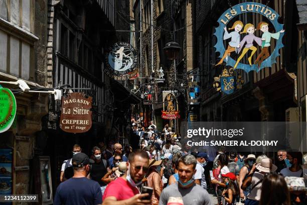 Tourists and visitors, some wearing facemasks, gather in a busy street in the centre of Mont-Saint-Michel, in Normandy, northwestern France, on July...