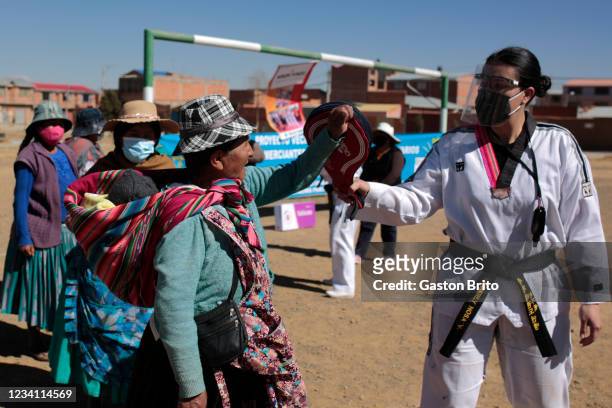 Woman wearing face mask and traditional clothes give a hits a pad held by taekwondo instructor Kimberly Nosa of Warmi Power on July 22, 2021 in El...
