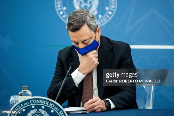 Italian Prime Minister Mario Draghi touches his face mask during a press conference with Italy's Justice Minister and Italy's Health Minister at the...