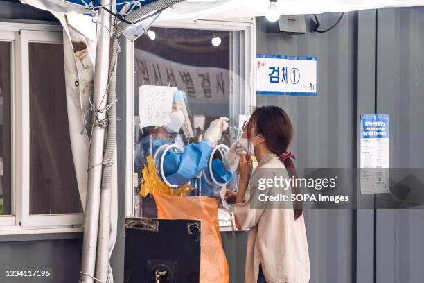 Health worker collects a nasal sample from a woman at a makeshift testing site in Seoul. South Korea is reporting 1,842 newly confirmed COVID19...