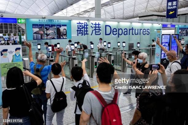 This picture taken on July 22 shows people waving goodbye as passengers make their way through the departure gates of Hong Kong's International...