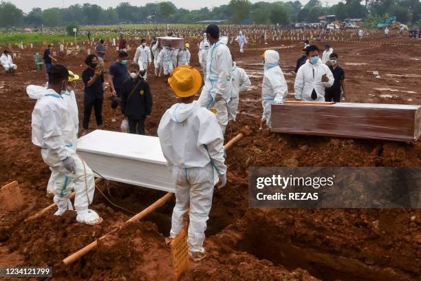 Funeral workers prepare to bury deceased COVID-19 coronavirus victims who were brought by ambulance directly from hospitals, at the Pedurenan public...