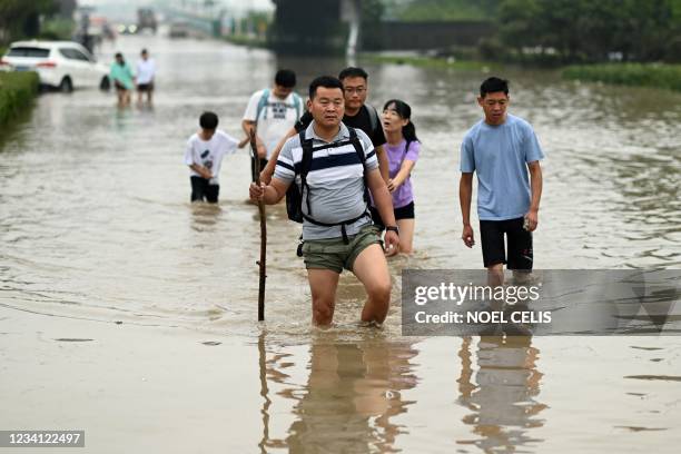 People cross a flooded street following heavy rains which caused flooding and claimed the lives of at least 33 people earlier in the week, in the...