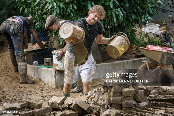 Helper empties a bucket with muddy water during clearing work in Swisttal-Odendorf, near Euskirchen, North Rhine-Westphalia, western Germany, on July...