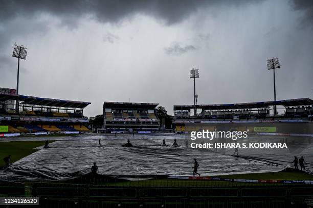 Sri Lanka's ground staff personnel cover the ground as rain stops play during the third one-day international cricket match between Sri Lanka and...