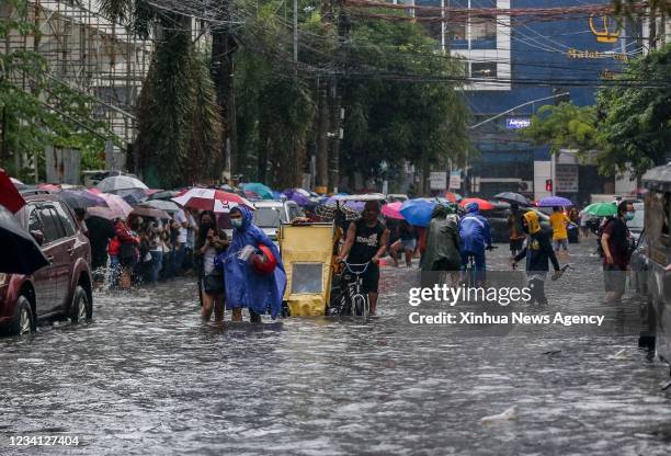 People wade through the flood brought by heavy monsoon rains in Manila, the Philippines, July 21, 2021.