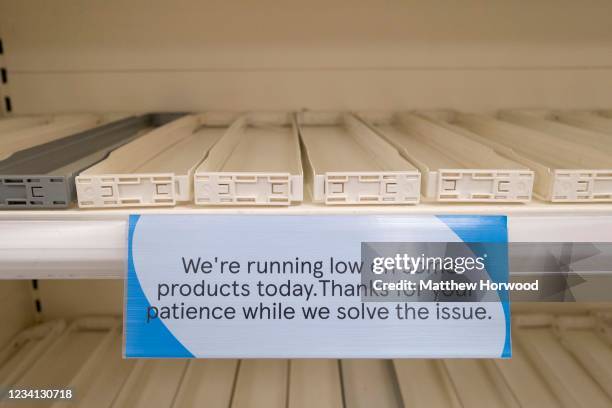Close-up of a sign attached to an empty shelf in a Tesco store explaining that they are running low on stock on certain items on July 23, 2021 in...