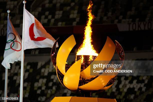 Picture shows the Olympic Flame and Cauldron next to the Japanese and Olympic flags during the opening ceremony of the Tokyo 2020 Olympic Games, at...