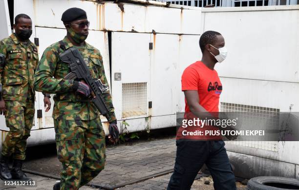 Armed Nigerian naval officers lead a suspected pirate to the courtroom for sentencing of the hijacking of a Chinese fishing vessel with 18 crew...