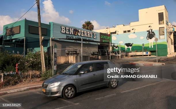 Motorist drives past a closed "Ben & Jerry's" ice-cream shop in the Israeli city of Yavne, about 30 kilometres south of Tel Aviv, on July 23, 2021. -...