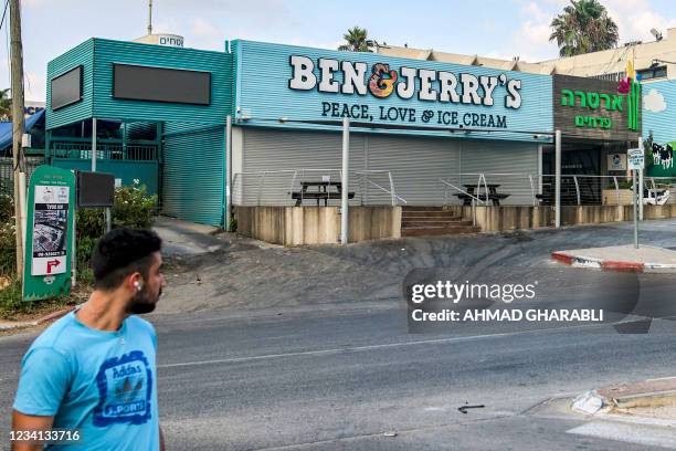 Man walks past a closed "Ben & Jerry's" ice-cream shop in the Israeli city of Yavne, about 30 kilometres south of Tel Aviv, on July 23, 2021. - On...