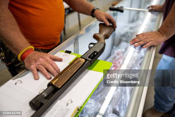 Worker shows a shotgun for sale to a customer at Knob Creek Gun Range in West Point, Kentucky, U.S., on Thursday, July 22, 2021. Firearm sales have...