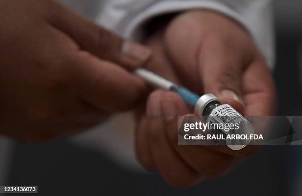 Health worker prepares to inoculate a pregnant woman with the Pfizer-BioNTech vaccine against COVID-19 at a vaccination center in Bogota, on July 23,...